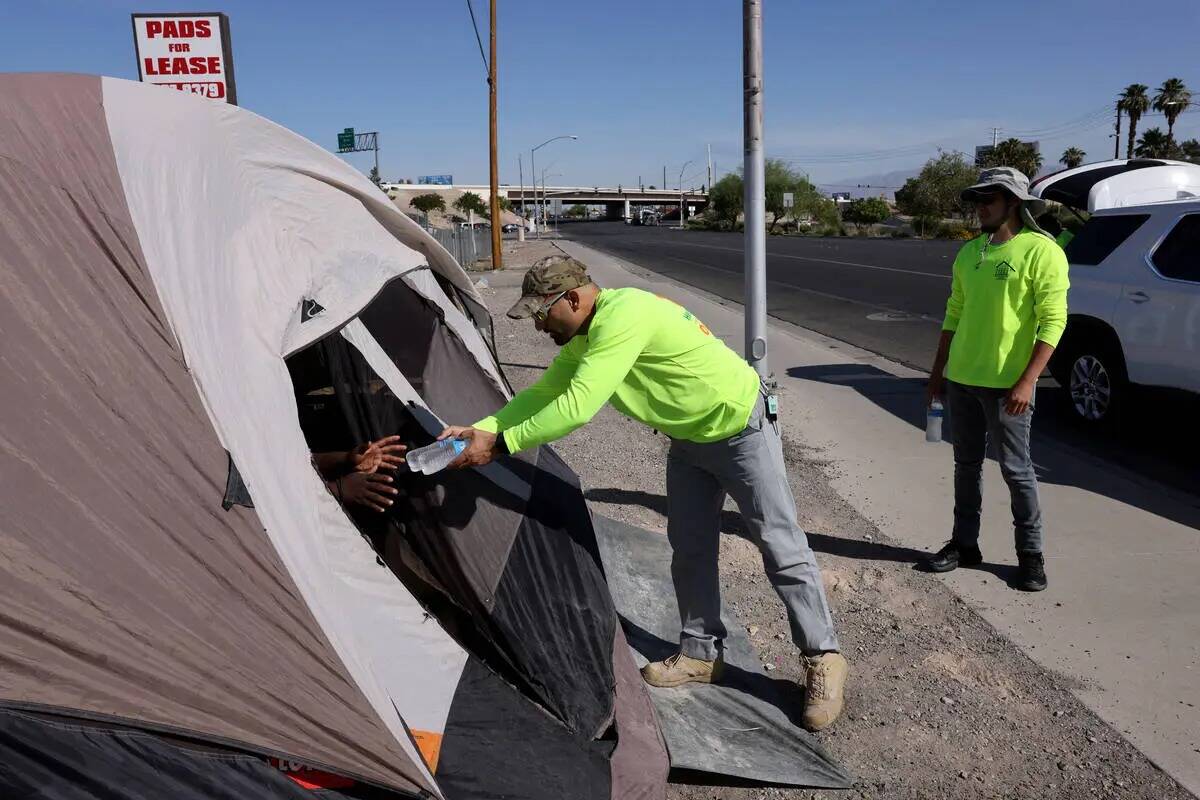 Abdul Hamdard, de HELP of Southern Nevada, ofrece agua a una persona refugiada en una tienda de ...