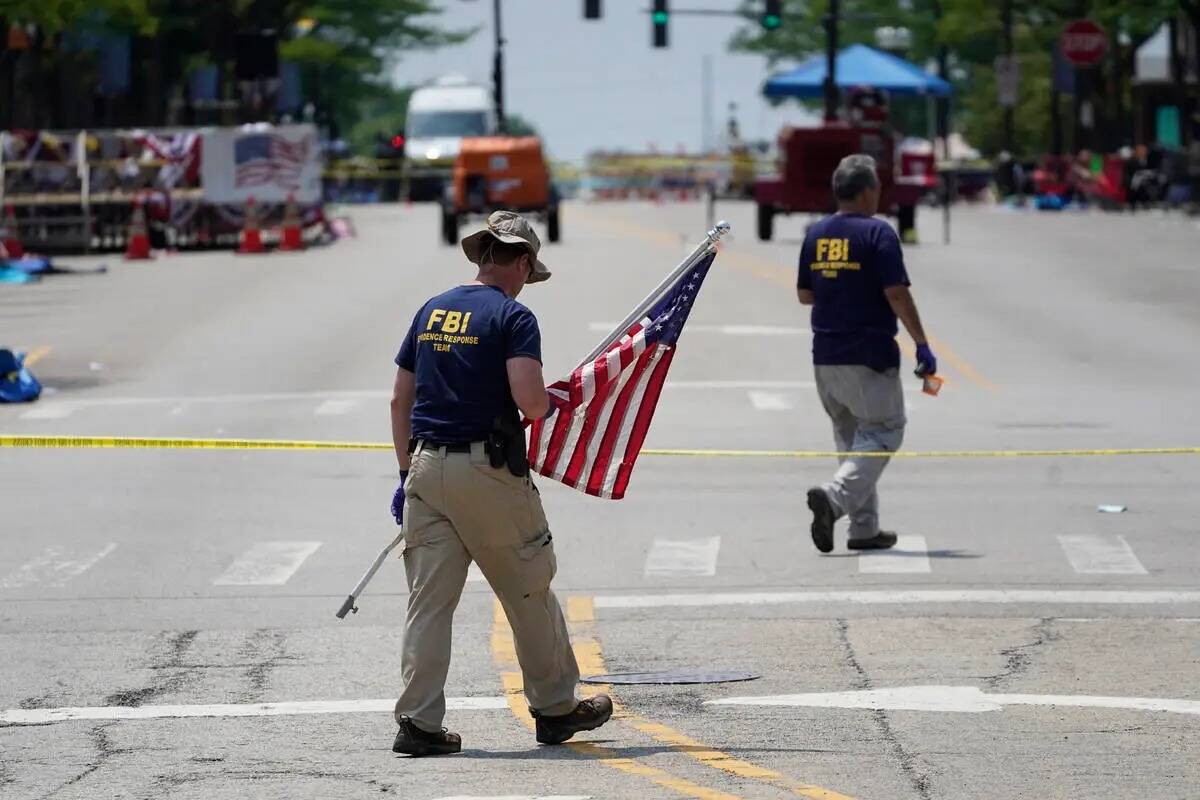Un miembro del equipo de respuesta de evidencias del FBI retira una bandera estadounidense un d ...