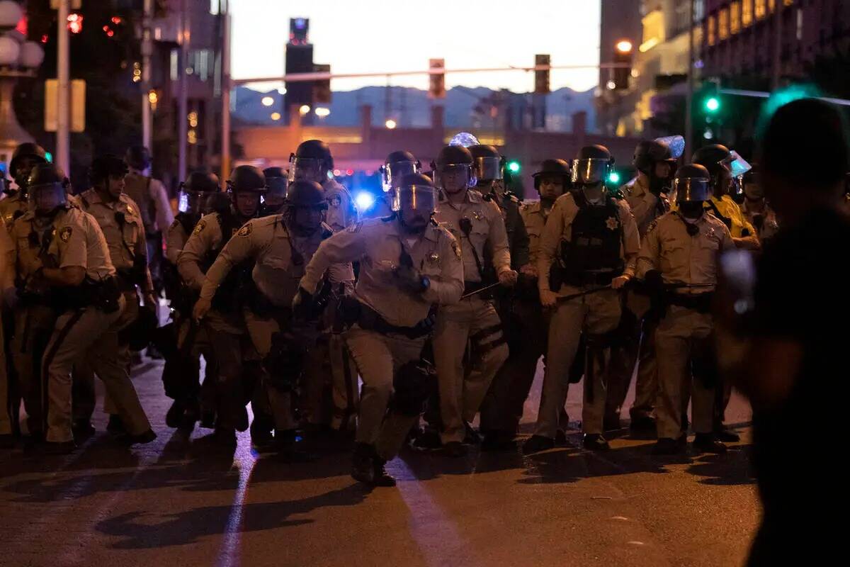Agentes de policía de Las Vegas corren hacia la multitud de manifestantes que tomaron el Strip ...