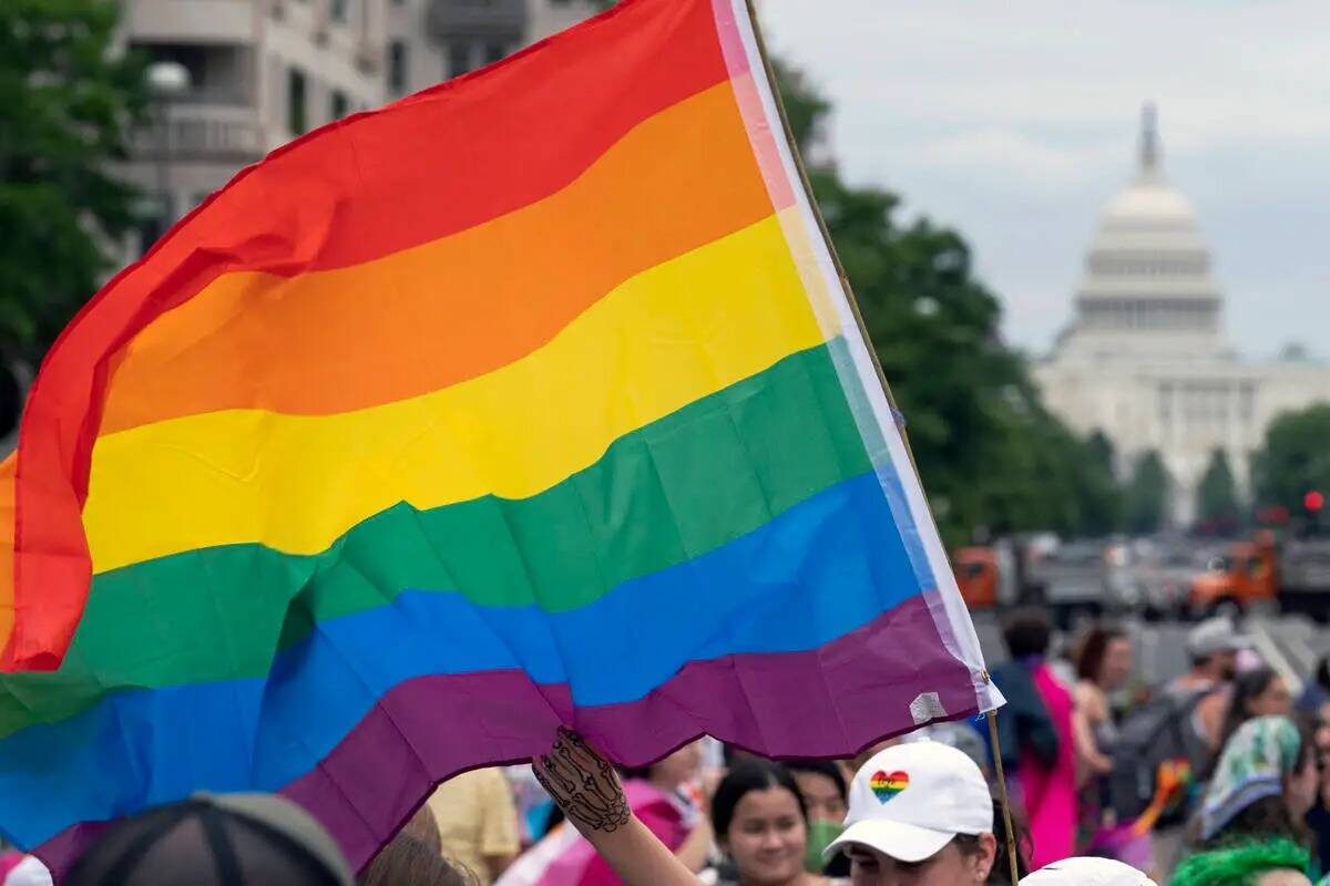 ARCHIVO - Con el Capitolio de Estados Unidos de fondo, una persona ondea una bandera arcoíris ...