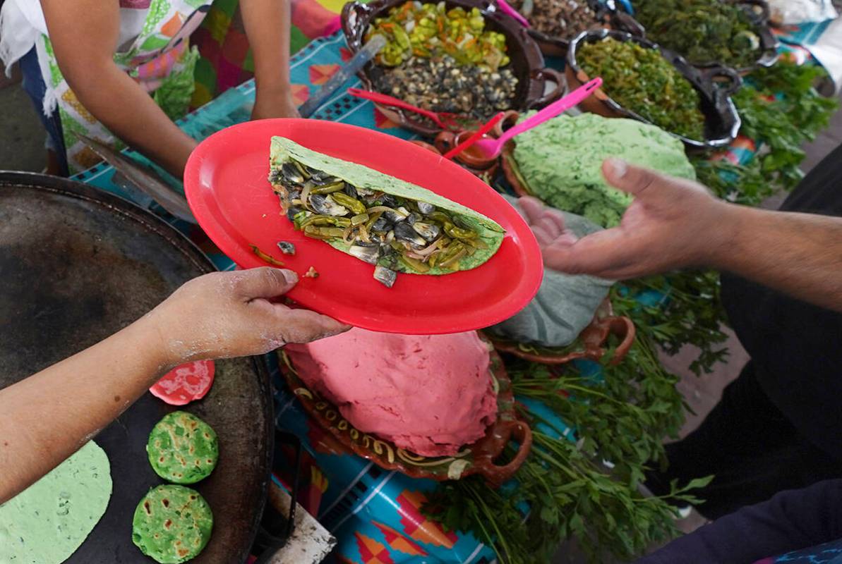 Un vendedor sirve nopales y huitlacoche en una tortilla de color verde en la Feria de Comida Pr ...