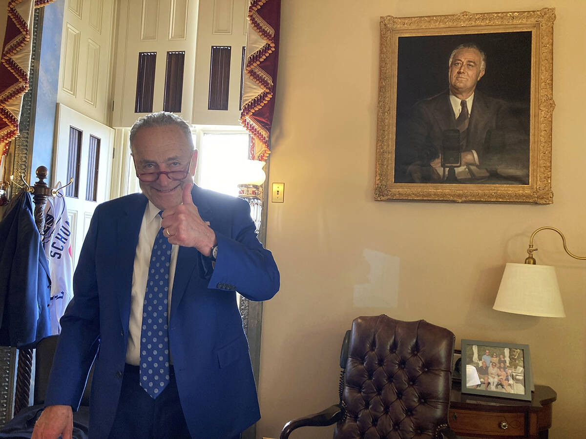 El senador Chuck Schummer hace una señal de triunfo en su oficina en el Senado, el domingo 7 d ...