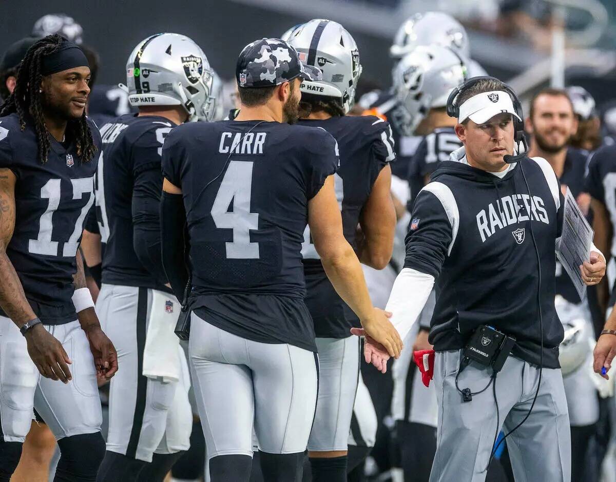 El quarterback de los Raiders, Derek Carr (4), se da la mano con el entrenador Josh McDaniels d ...