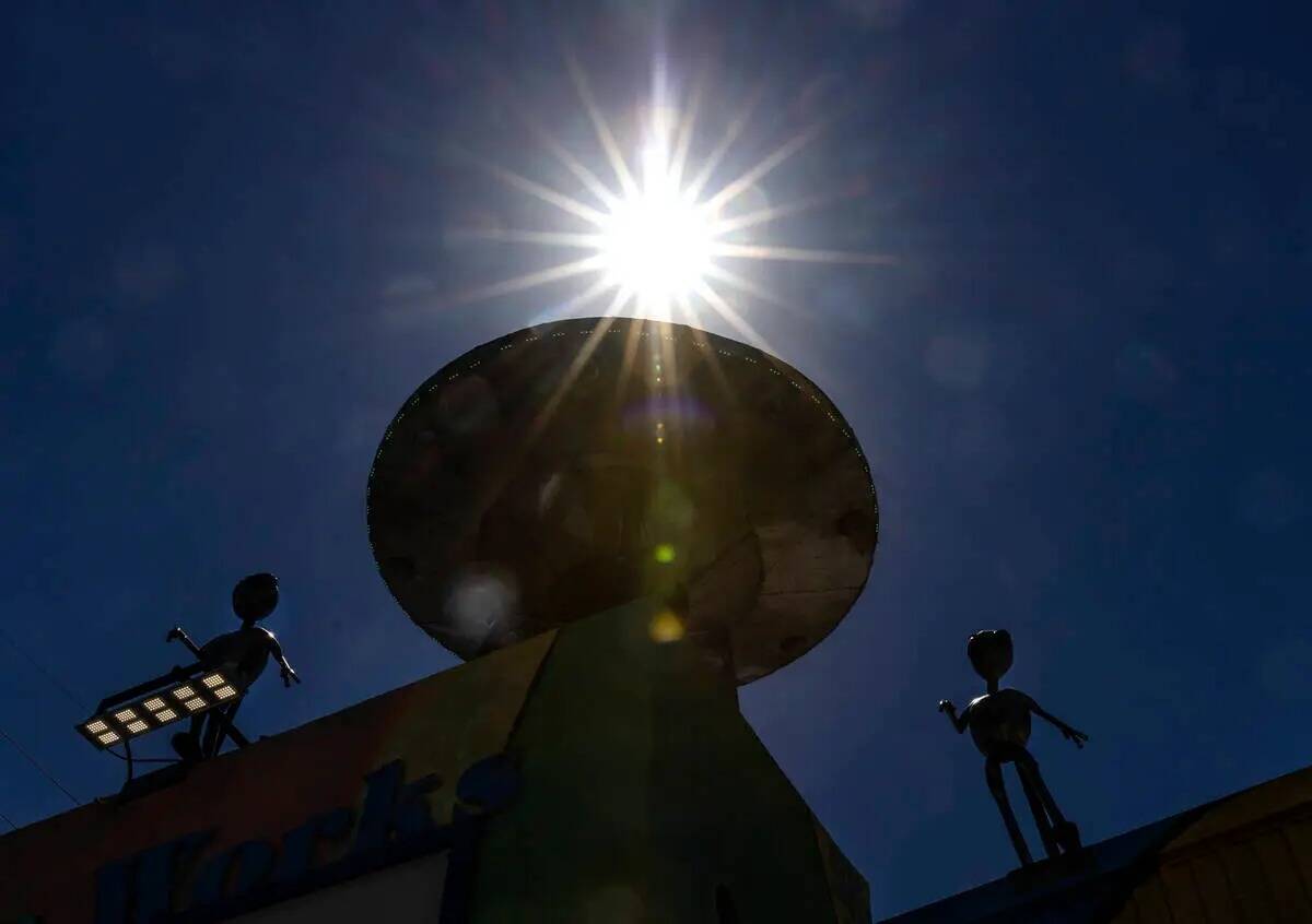Los rayos de luz del sol de la tarde atraviesan una escultura metálica de Aliens y su nave fue ...