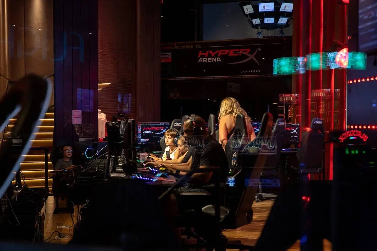 Los jugadores juegan en la sección pública del HyperX Arena Las Vegas mientras un panel de la ...