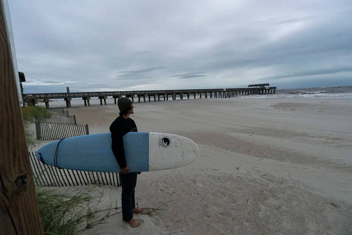Alex Tatlock, de Savannah, Ga., revisa para hacer surf, y decide no hacerlo, mientras se siente ...