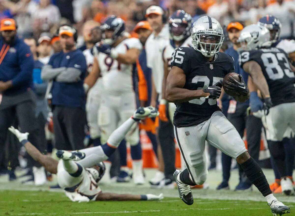 El running back de los Raiders, Zamir White (35), tropieza con el safety de los Denver Broncos, ...