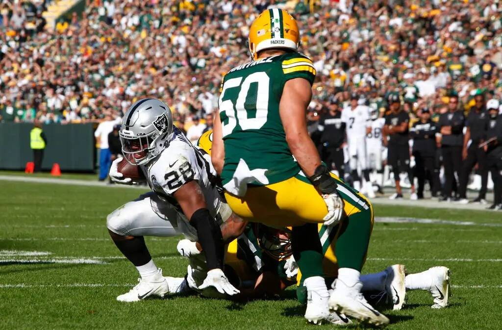 El running back de los Oakland Raiders Josh Jacobs (28) lucha por más yardas mientras es abord ...