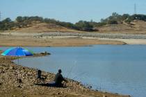 Un hombre coloca su caña de pescar a lo largo de la línea de la orilla de Folsom Lake que nor ...
