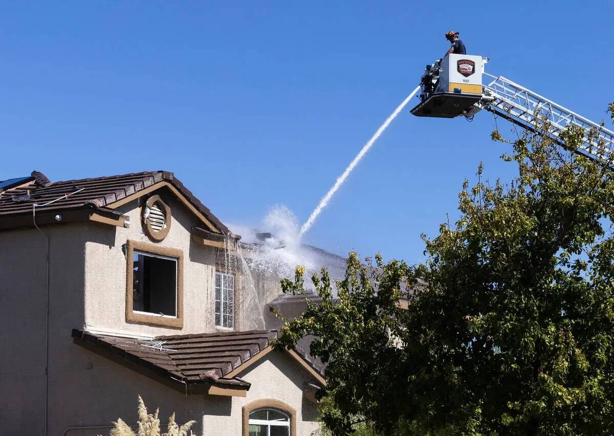 Un bombero de Las Vegas rocía agua en una casa de dos pisos donde dos personas fueron encontra ...