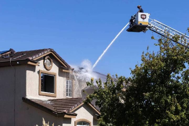 Un bombero de Las Vegas rocía agua en una casa de dos pisos donde dos personas fueron encontra ...