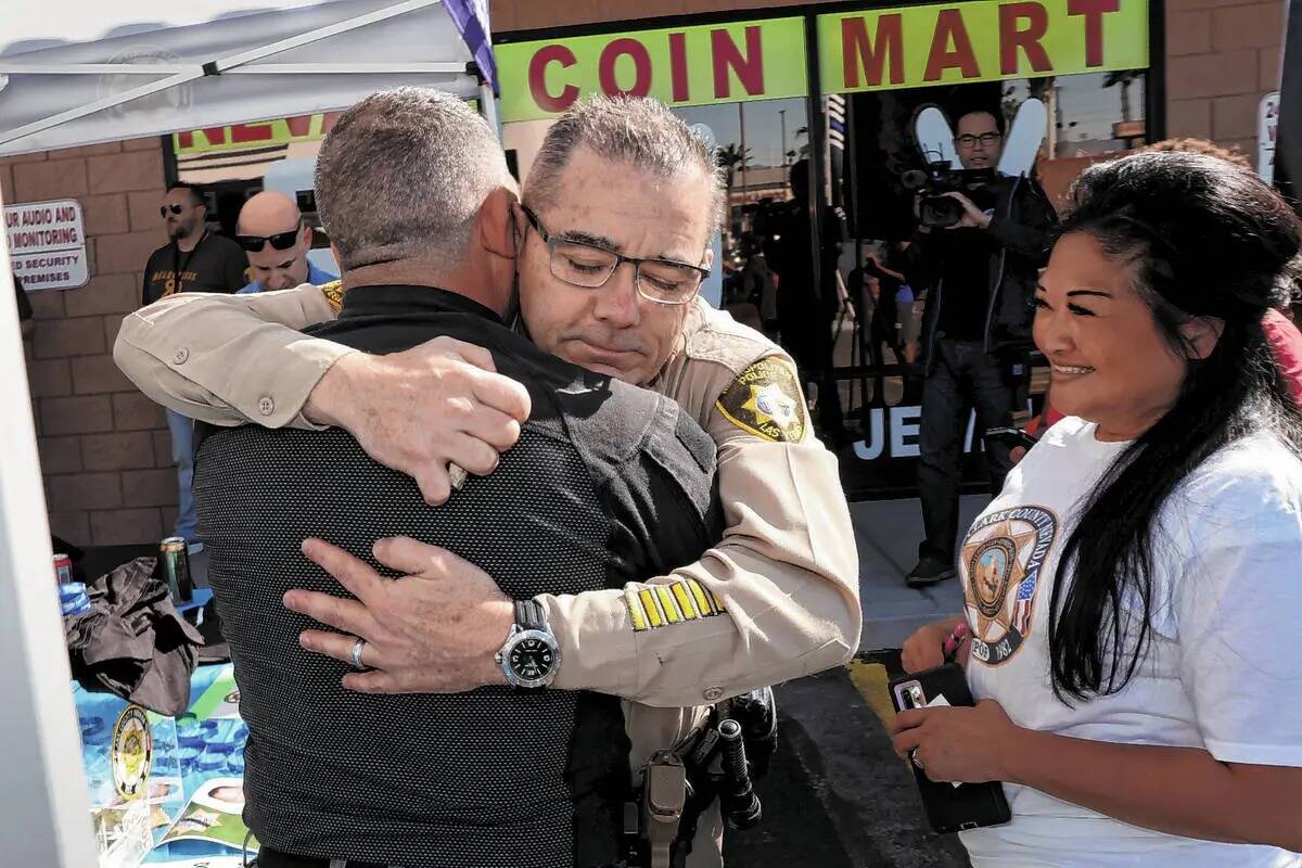 El alguacil adjunto de la policía de Las Vegas, Andrew Walsh, de frente, abraza al agente de p ...