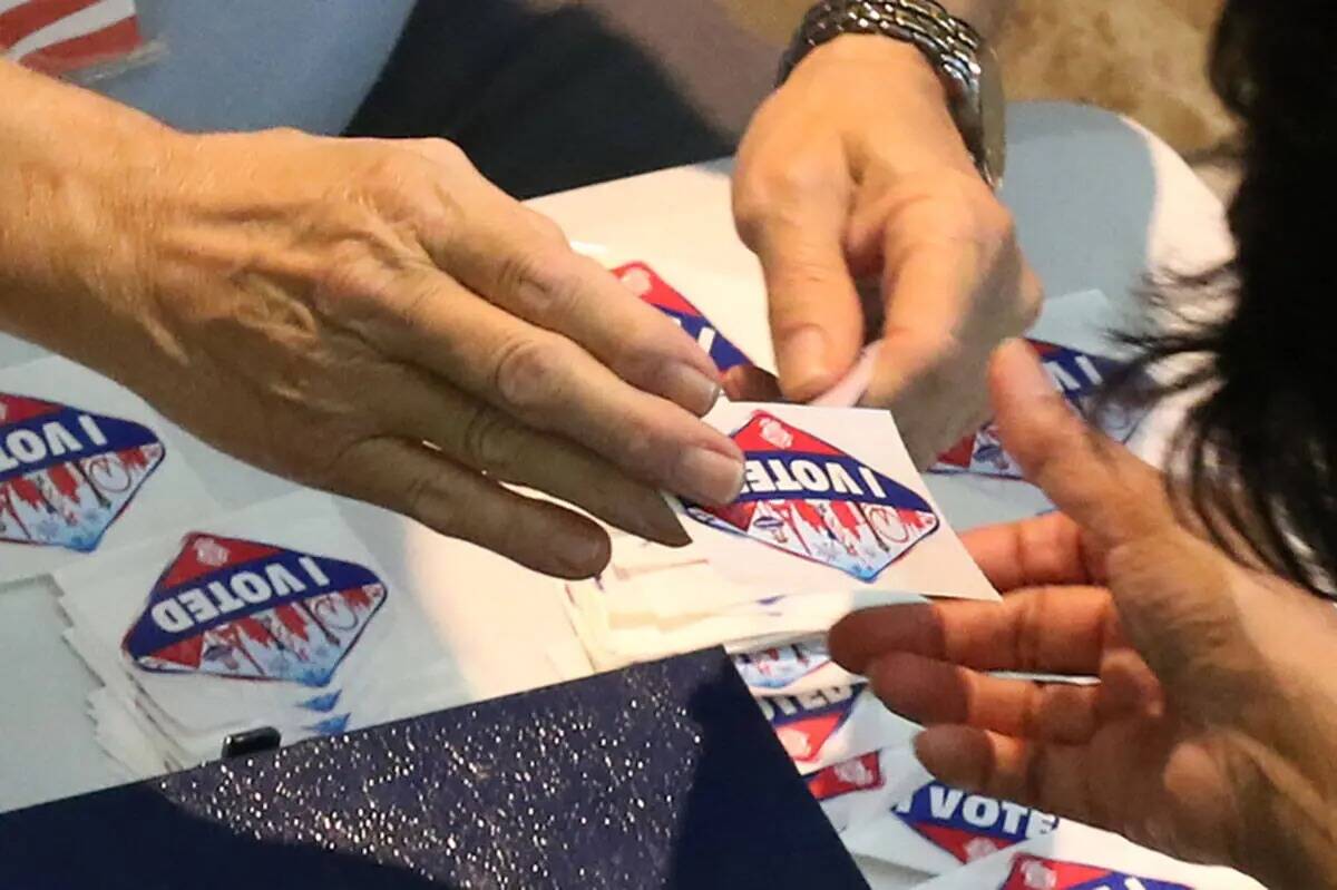 Un trabajador entrega la calcamonía "I Voted " a un votante en un centro de votación en Galle ...