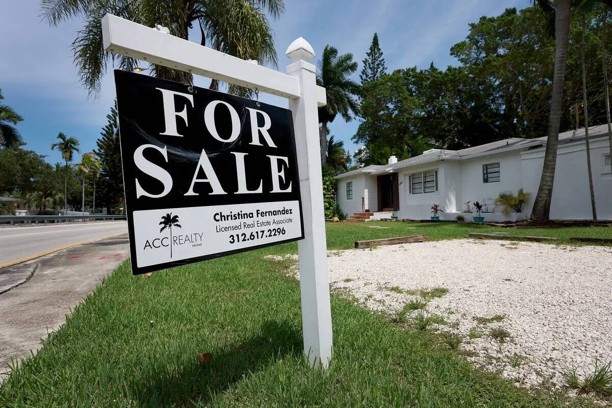 Un letrero de "se vende" cuelga delante de una casa el 21 de junio de 2022 en Miami. Las tasas ...