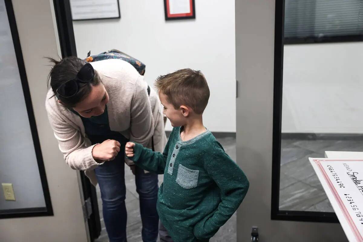 Henry Williams, de seis años, choca el puño con su madre Heather Williams en la Cruz Roja del ...