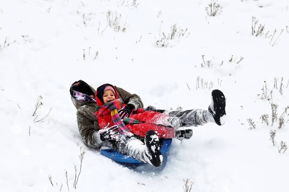 Greyson Murdock, de tres años, y su madre Logan Murdock se deslizan en trineo en la nieve reci ...