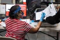 Una trabajadora electoral del Condado Clark revisa las papeletas mientras los trabajadores se p ...