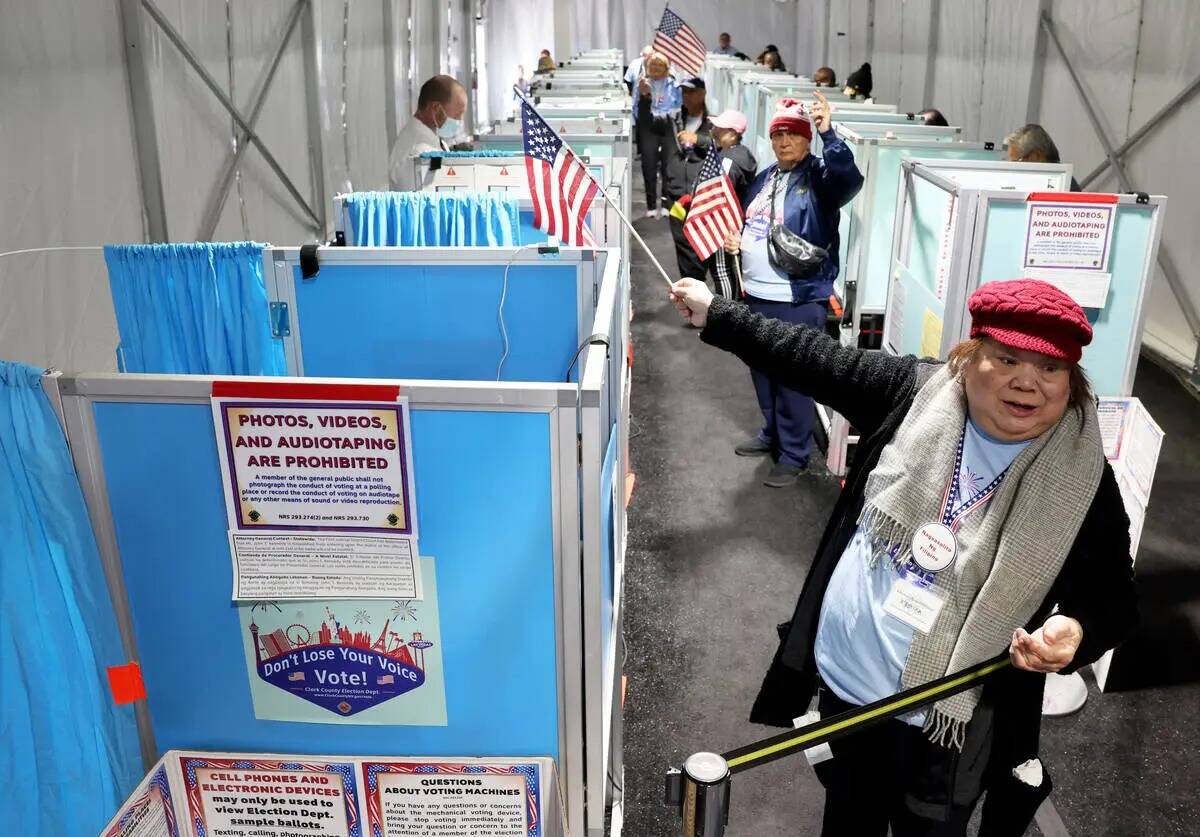 Marissa Mendoza dirige a un votante hacia una máquina de votación abierta mientras los votant ...