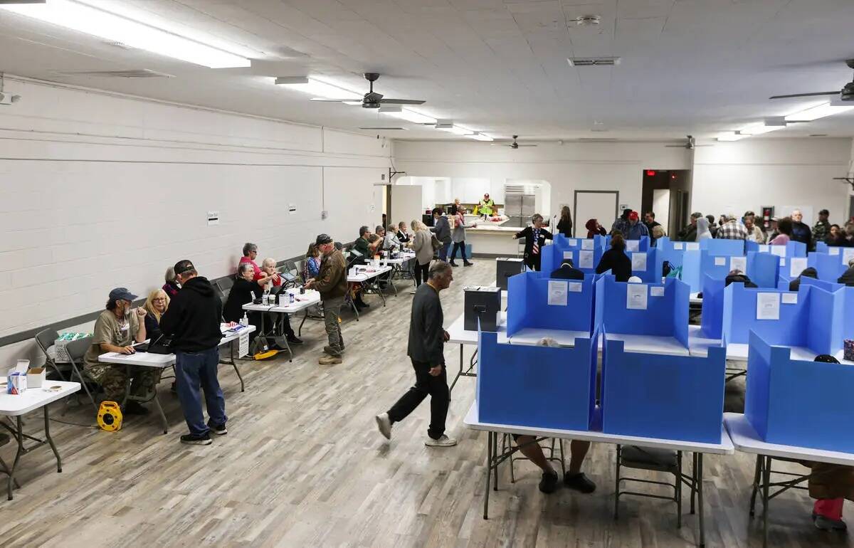 Los votantes del Condado Nye hacen fila y se registran con los trabajadores electorales para em ...