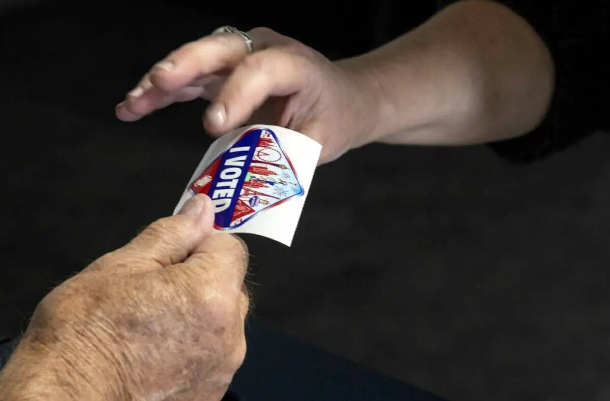 Un votante acepta una calcomanía de "I voted" en el último día de votación anticipada, el v ...