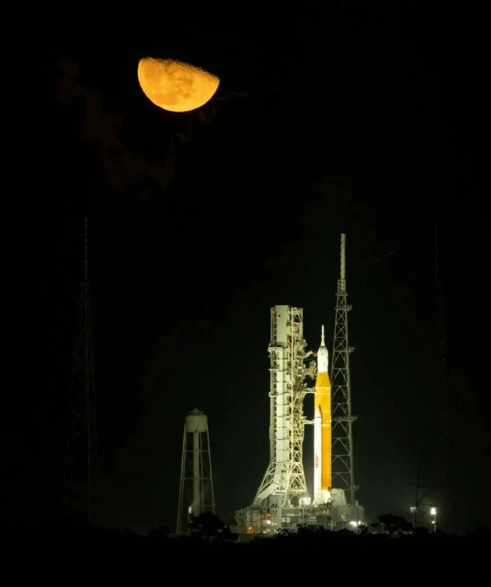 La luna se eleva sobre el cohete del Sistema de Lanzamiento Espacial (SLS) de la NASA con la na ...