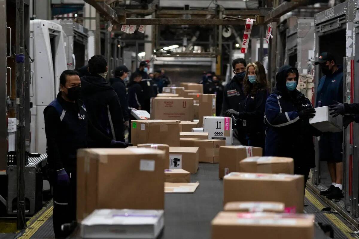 Los empleados clasifican los paquetes para su entrega en el centro regional de FedEx en el Aero ...