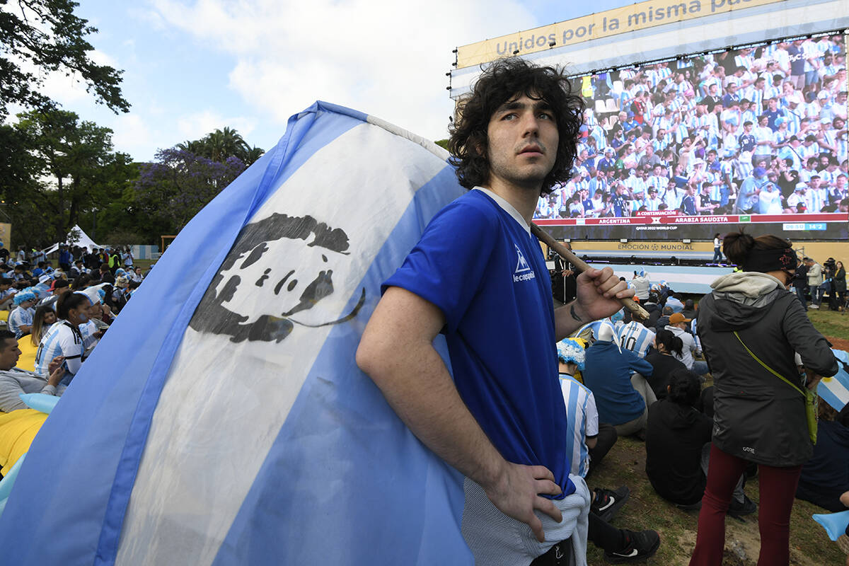 Un fanático del fútbol argentino sostiene una bandera de Maradona mientras ve a la selección ...