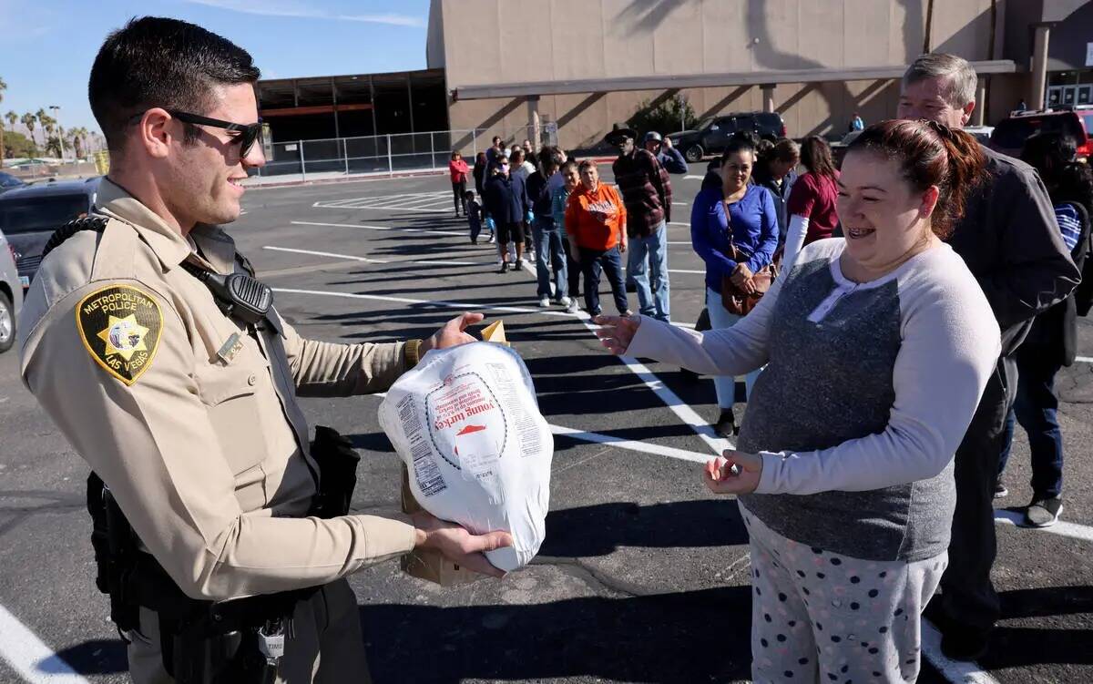 El agente de policía de Las Vegas J. Altman, le da una comida de Thanksgiving a Michelle Ramir ...