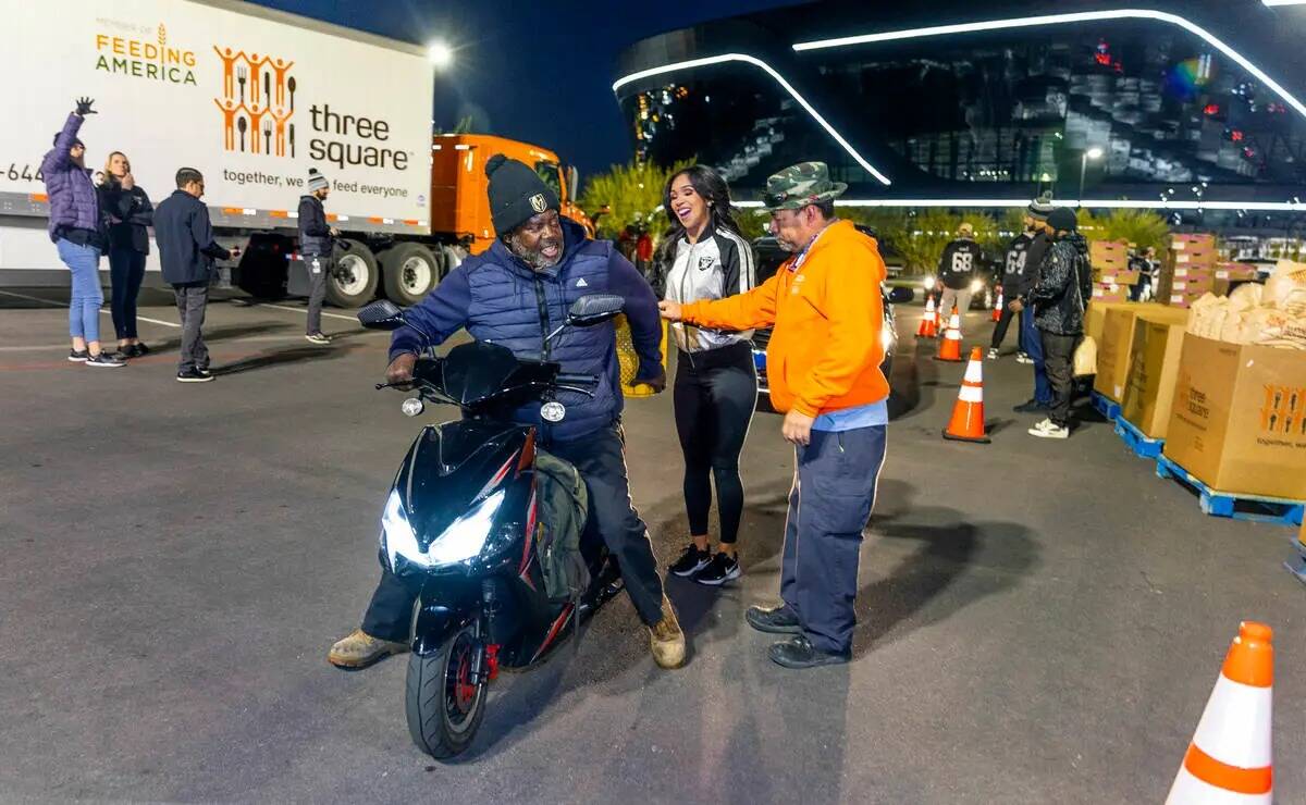 (Izquierda a derecha) Terrence Hazel recibe lo último de su comida de la Raiderette Cierra y A ...