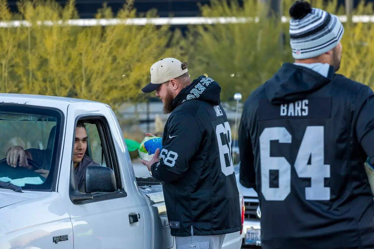 El centro de los Raiders Andre James (68) entrega un pavo con el guard Alex Bars (64) cerca mie ...