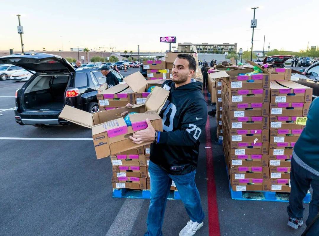 El offensive tackle de los Raiders Sebastián Gutiérrez (70) entrega una caja de pavos mientra ...