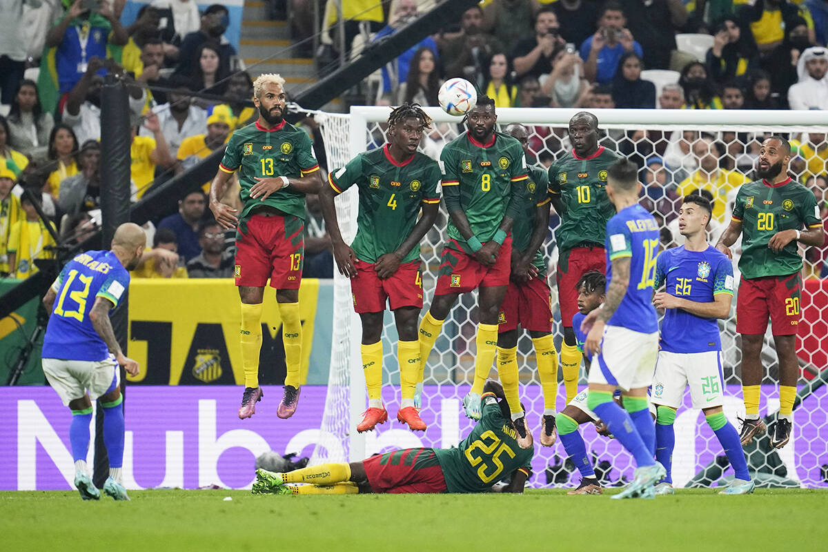 El muro defensivo de Camerún salta para bloquear un tiro libre del brasileño Dani Alves, a la ...