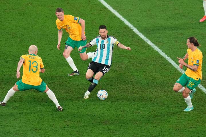 El argentino Lionel Messi, centro, controla el balón rodeado por el australiano Aaron Mooy, a ...