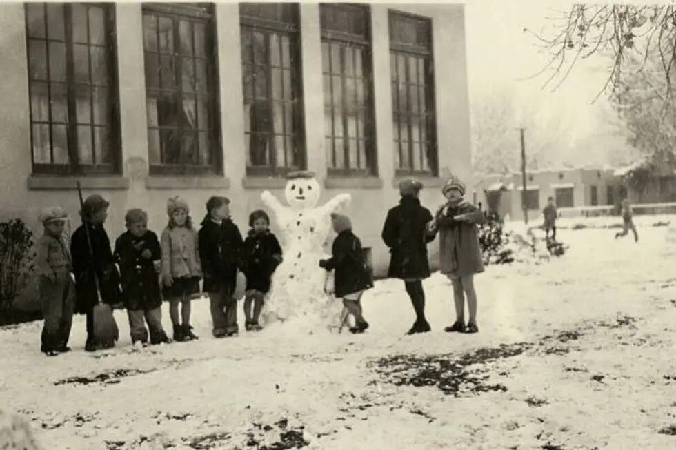 Niños de una escuela construyen un muñeco de nieve fuera de una escuela en Fifth Street en La ...