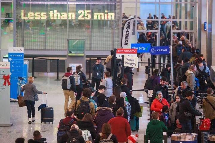 Los viajeros esperan en fila para registrarse para sus vuelos en la Terminal Uno antes de las v ...