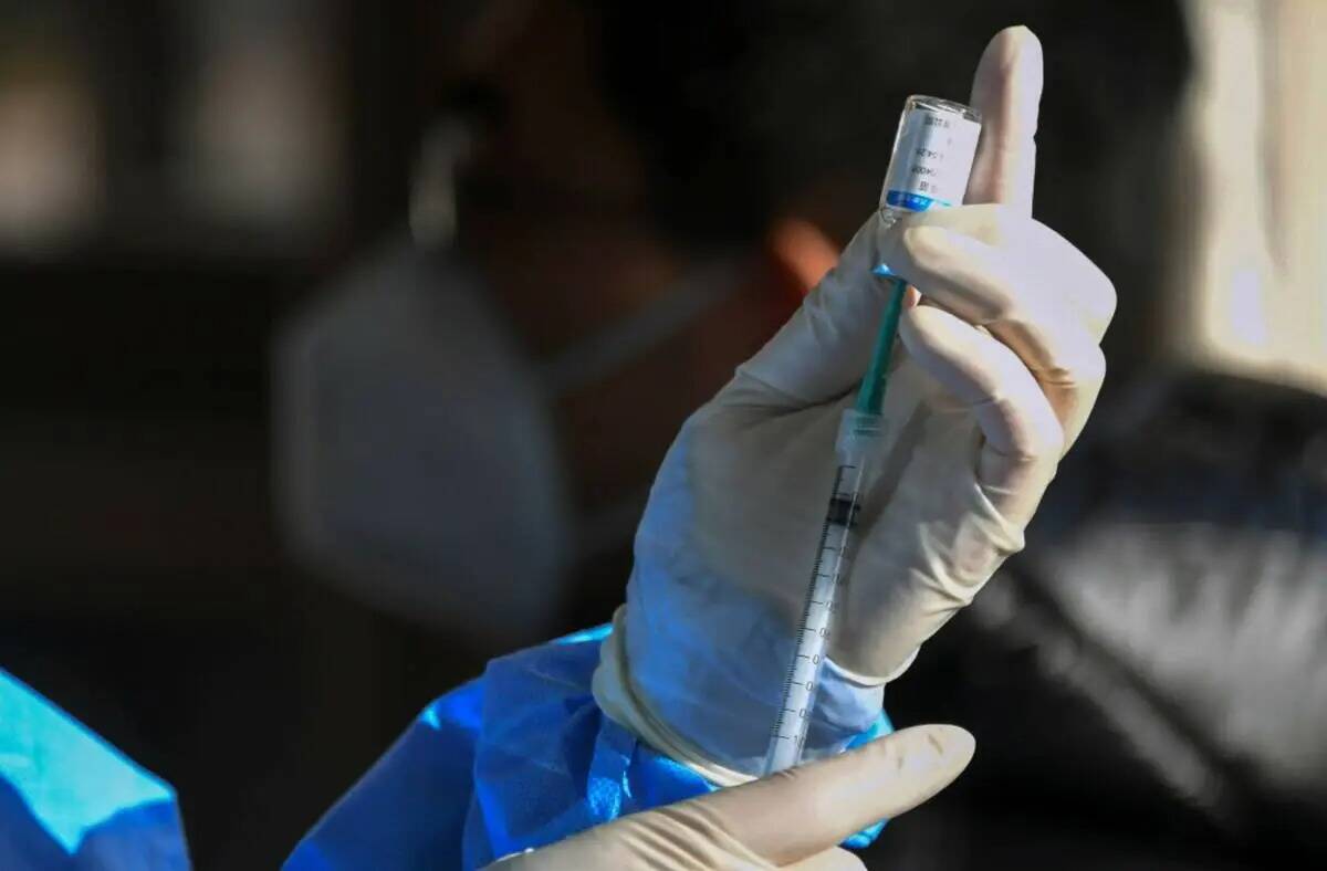 Un trabajador médico se prepara para administrar una segunda dosis de refuerzo de la vacuna CO ...