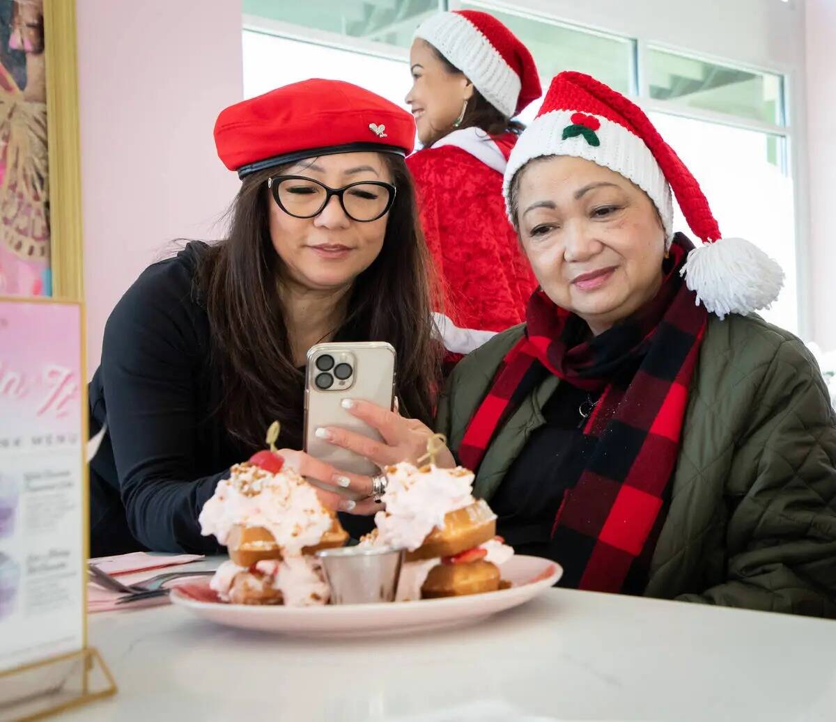 Portia Wigget, izquierda, toma una foto del Strawberry Shortcake Waffle en Cafe Lola el viernes ...