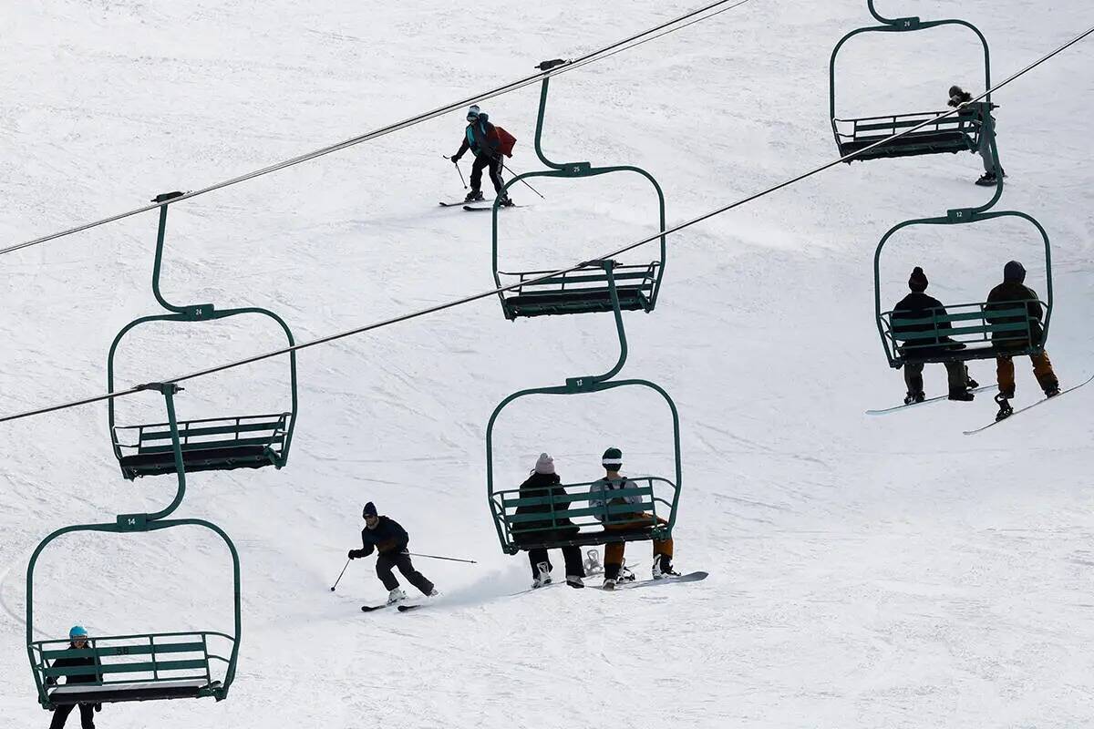 Esquiadores y practicantes de snowboard disfrutan de la pista mientras la gente sube a las tele ...