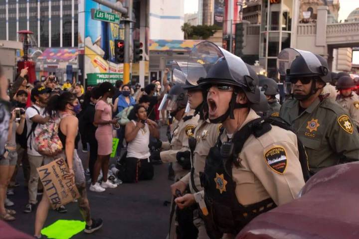 Un agente de la Policía Metropolitana grita a los manifestantes que retrocedan mientras la pro ...