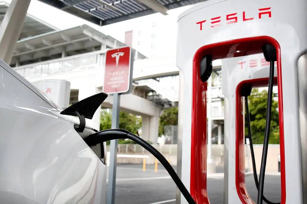 Un vehículo eléctrico Tesla Model 3 se carga en una estación Tesla Supercharger cerca de Hig ...