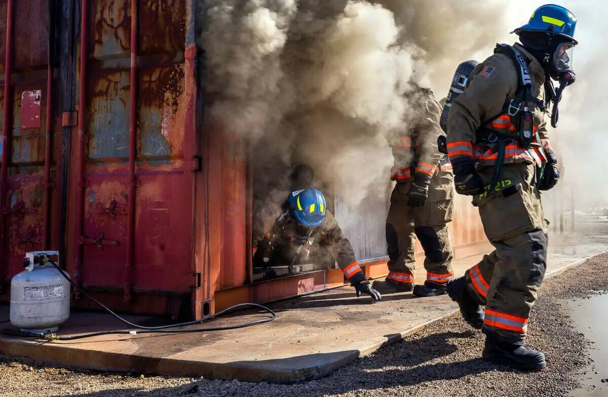 Los reclutas del Departamento de Bomberos del Condado Clark salen de un remolque lleno de humo ...