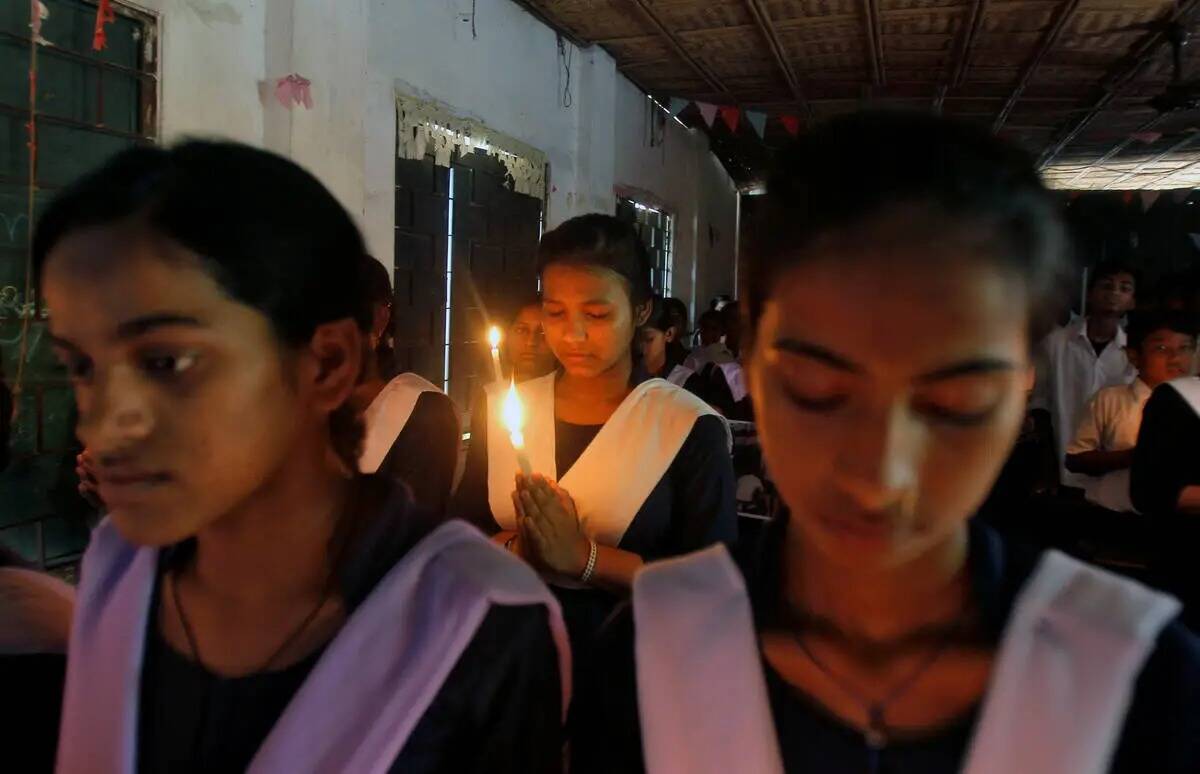 Alumnos sostienen velas mientras rezan durante una vigilia en solidaridad con las víctimas del ...