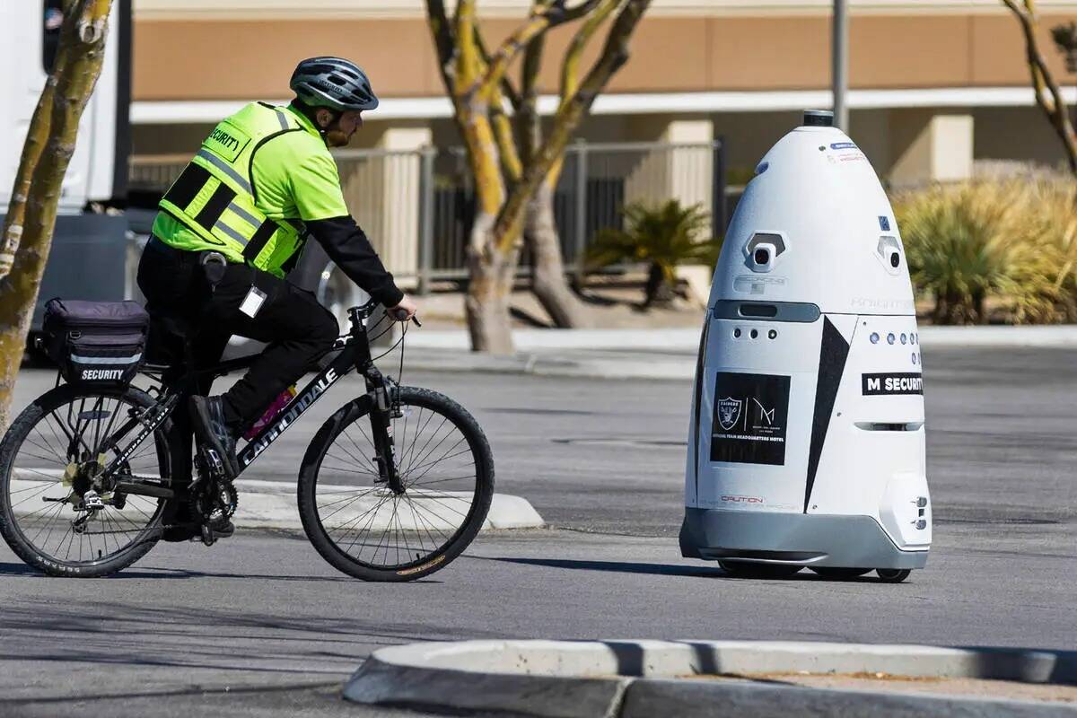 Un guardia de seguridad de M Resort pasa junto al robot autónomo de tamaño humano: M Bot, mie ...