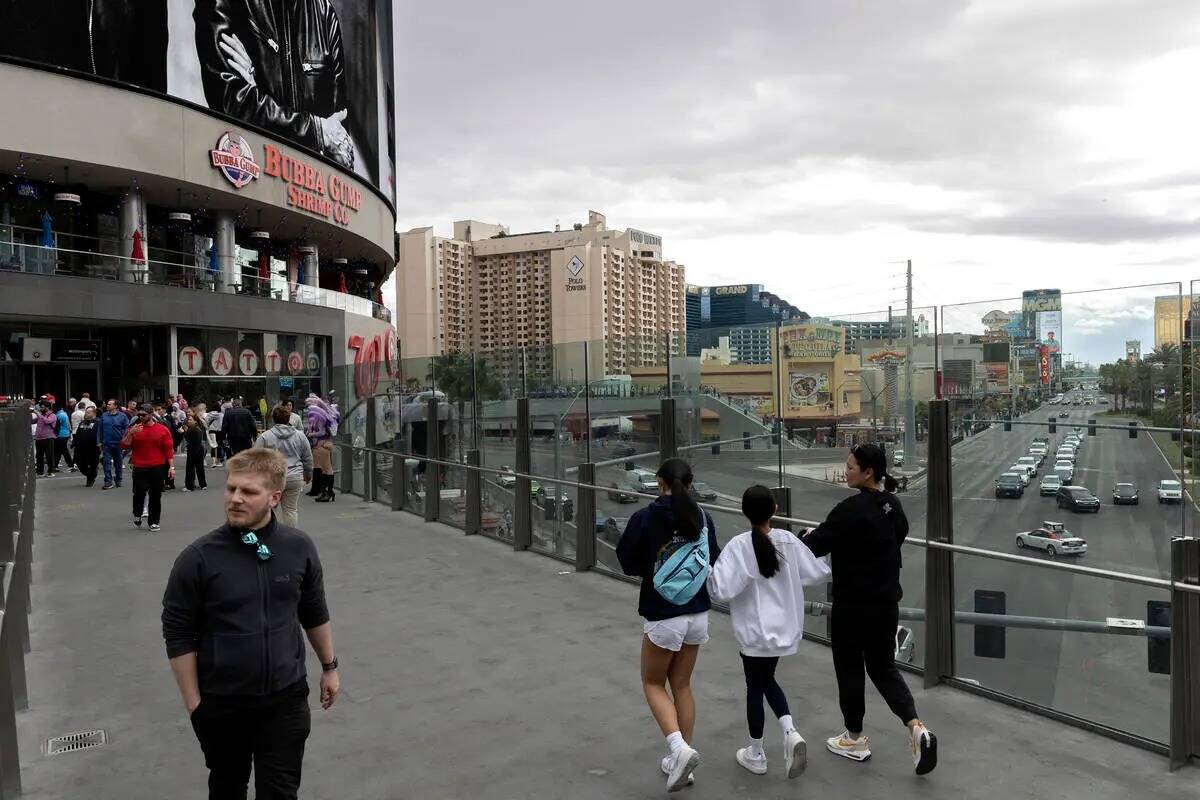 Peatones cruzan Las Vegas Boulevard junto a Harmon Corner, a la izquierda, un complejo comercia ...