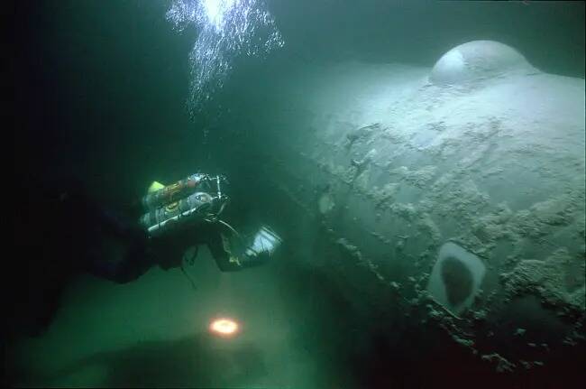 Un arqueólogo submarino del Servicio de Parques Nacionales examina un bombardero B-29, apodado ...