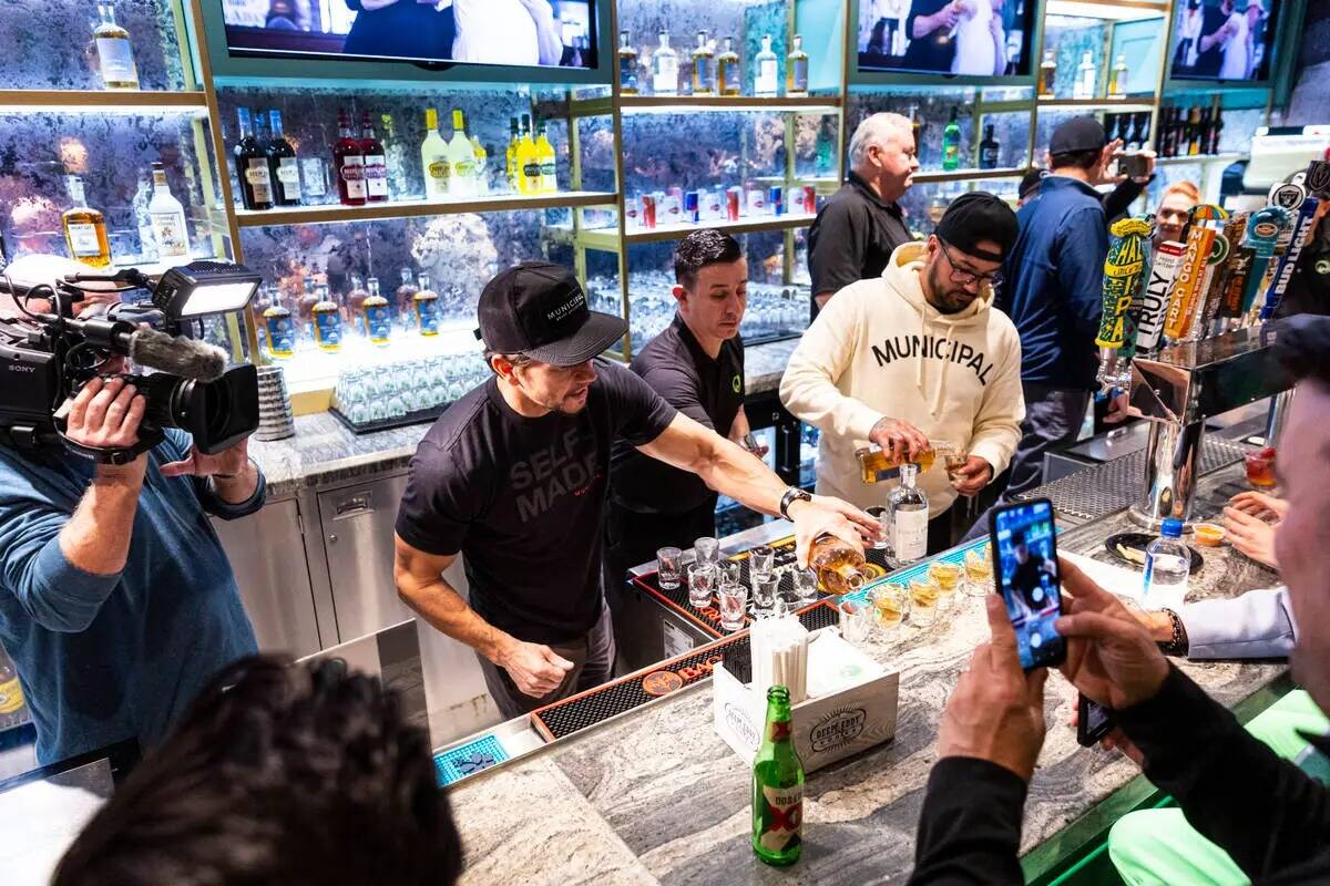 Mark Wahlberg, a la izquierda, sirve bebidas en el bar durante la celebración de la apertura d ...