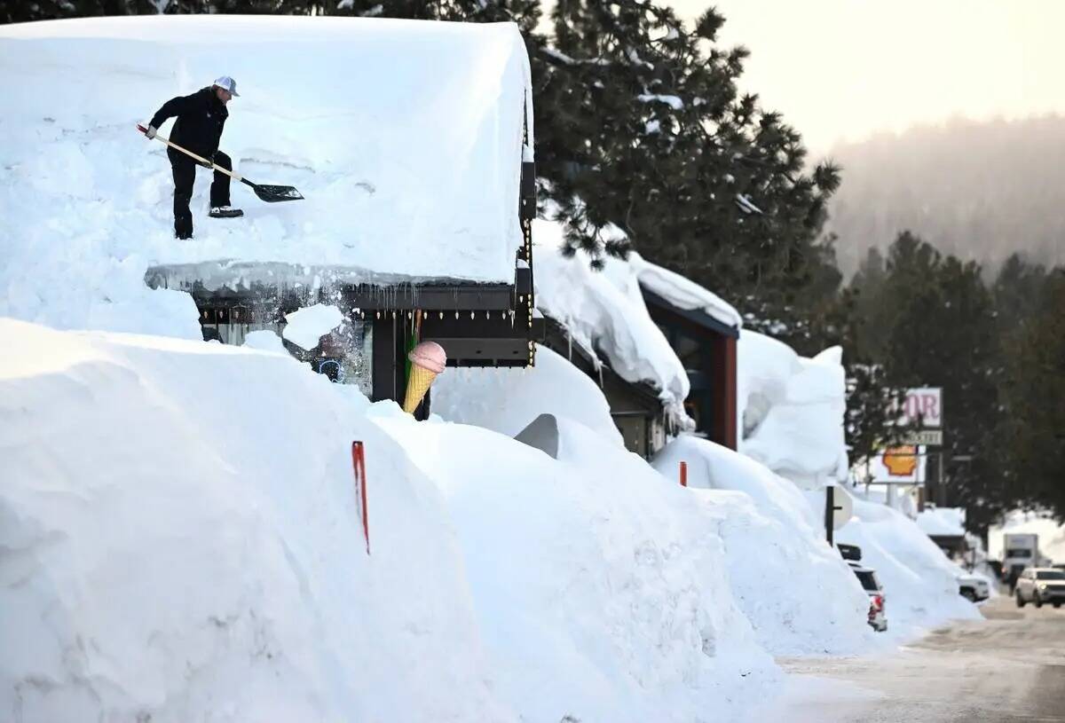 El dueño Brang Miller quita la nieve del tejado de Mammoth Fun Shop en Mammoth Lakes, Californ ...