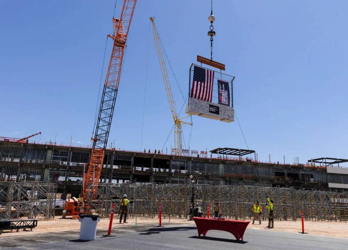 Equipos de construcción izan una barrera durante una ceremonia de término del edificio del pa ...