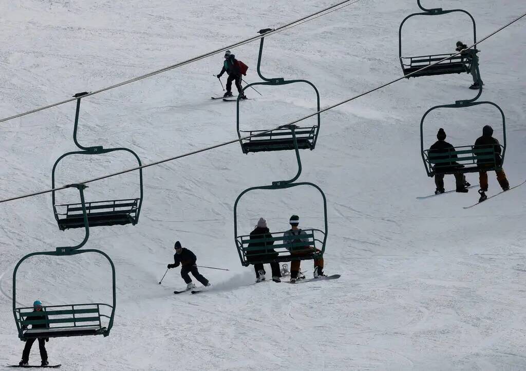 Esquiadores y snowboarders disfrutan de la pista mientras la gente sube a las telesillas el lun ...