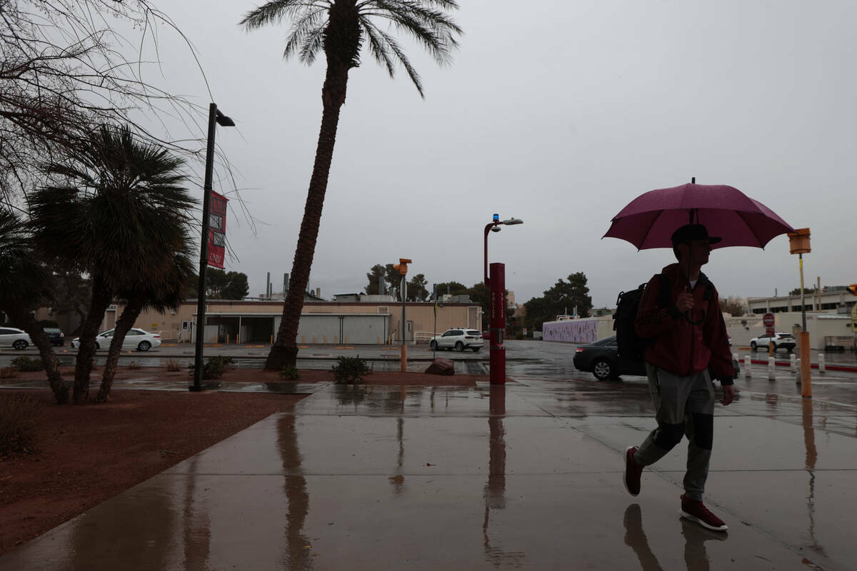 Un hombre con un paraguas camina bajo la lluvia por el campus de la UNLV, el 14 de marzo de 202 ...